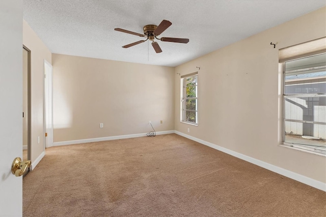 spare room with light carpet, a textured ceiling, and baseboards