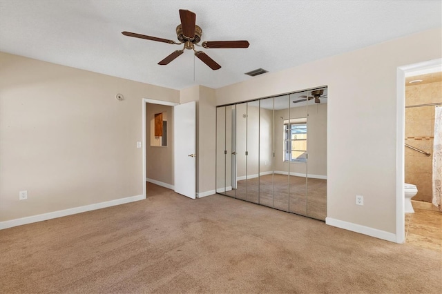 unfurnished bedroom with a closet, light colored carpet, visible vents, a textured ceiling, and baseboards