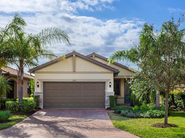 craftsman-style home featuring an attached garage, stone siding, decorative driveway, and stucco siding