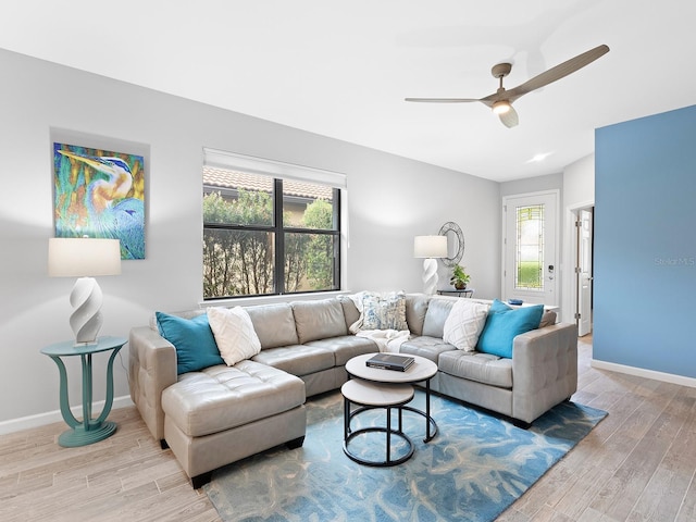 living room with baseboards, ceiling fan, and light wood-style floors