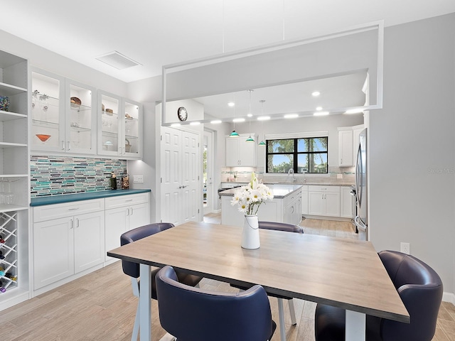 dining area with light wood finished floors and visible vents