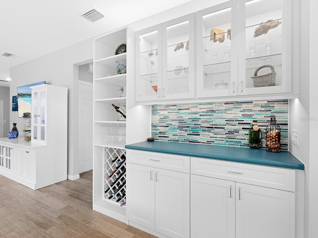 bar with tasteful backsplash, light wood-type flooring, and visible vents