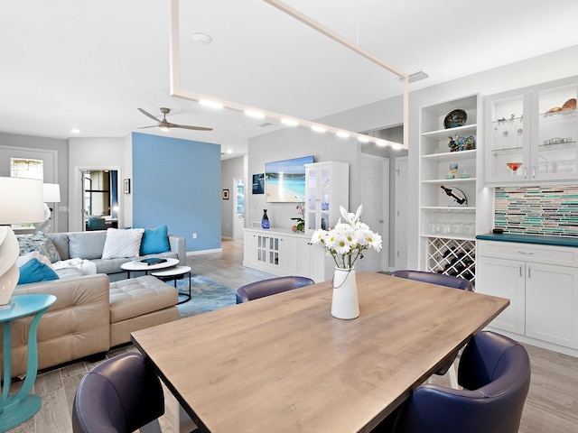 dining room featuring ceiling fan, built in shelves, light wood-type flooring, and baseboards