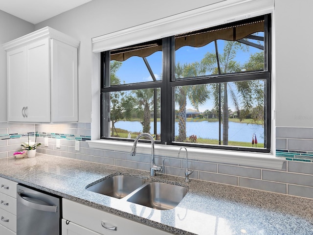 kitchen featuring a wealth of natural light, white cabinets, a water view, and a sink