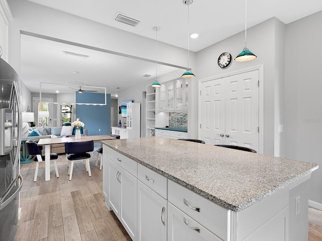 kitchen featuring light wood-type flooring, pendant lighting, white cabinets, and a kitchen island