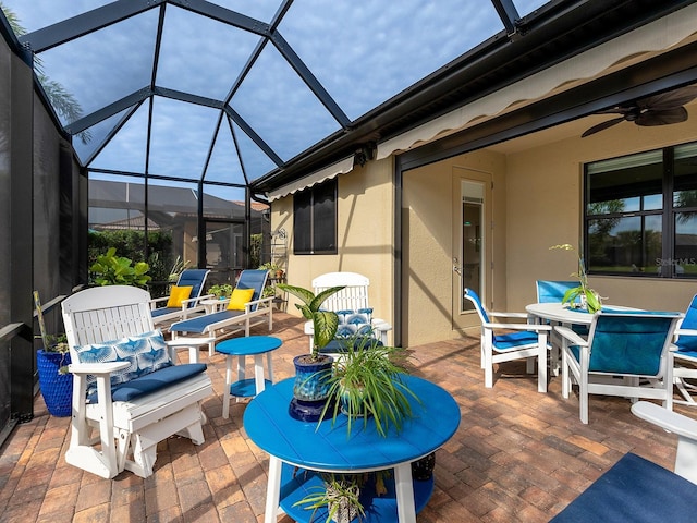 view of patio / terrace featuring ceiling fan, outdoor dining space, and a lanai