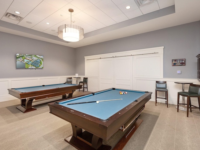 rec room featuring light carpet, visible vents, pool table, a tray ceiling, and a decorative wall