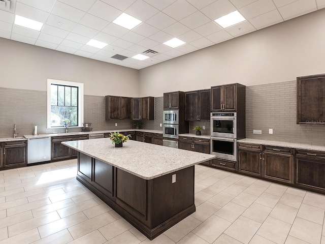 kitchen featuring a sink, visible vents, dark brown cabinets, appliances with stainless steel finishes, and a center island