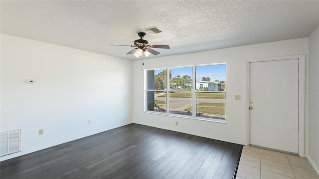 spare room with a ceiling fan, a textured ceiling, visible vents, and wood finished floors