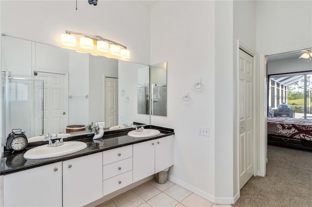 bathroom with double vanity, a closet, a shower stall, ensuite bath, and baseboards