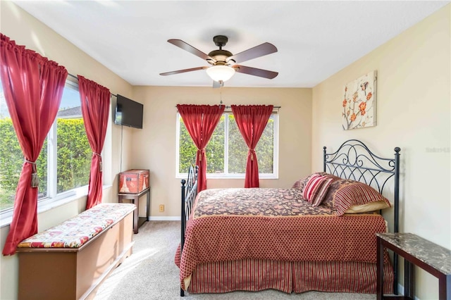 bedroom with multiple windows, light colored carpet, baseboards, and ceiling fan