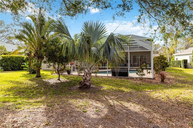 view of green lawn with a lanai