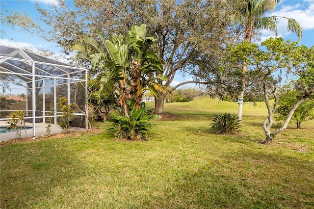 view of grassy yard with an outdoor pool and glass enclosure