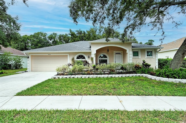 ranch-style home with a garage, driveway, a front yard, and stucco siding