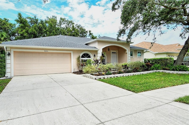 single story home with roof with shingles, stucco siding, concrete driveway, an attached garage, and a front lawn