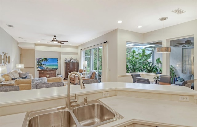 kitchen featuring visible vents, open floor plan, a sink, and light countertops