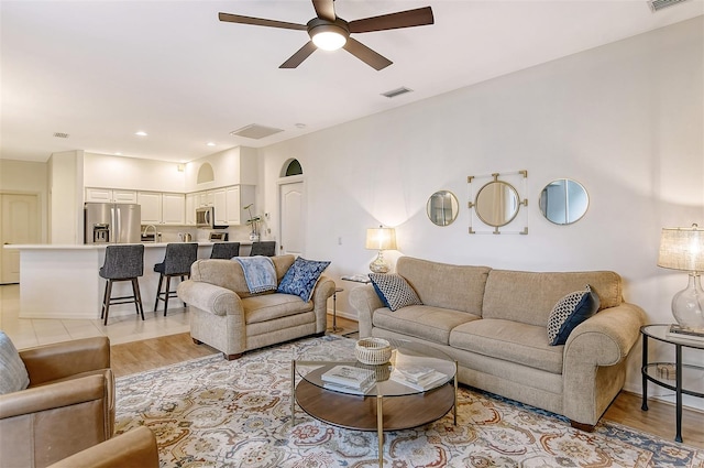 living room featuring a ceiling fan, visible vents, and light wood-style flooring