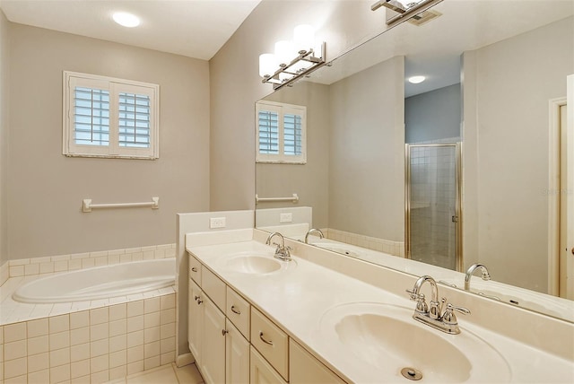 full bathroom with double vanity, a garden tub, a sink, and a stall shower