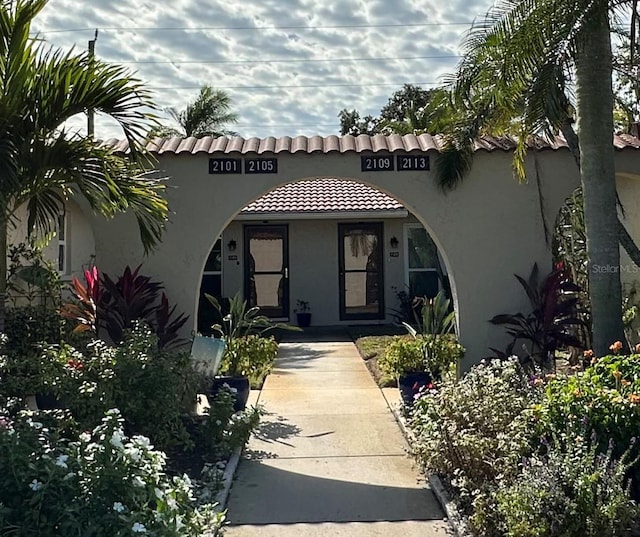 view of exterior entry with a tile roof and stucco siding