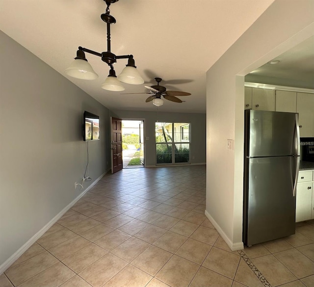 spare room with ceiling fan, light tile patterned flooring, and baseboards