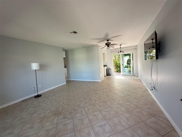 spare room with ceiling fan, light tile patterned floors, a textured ceiling, visible vents, and baseboards