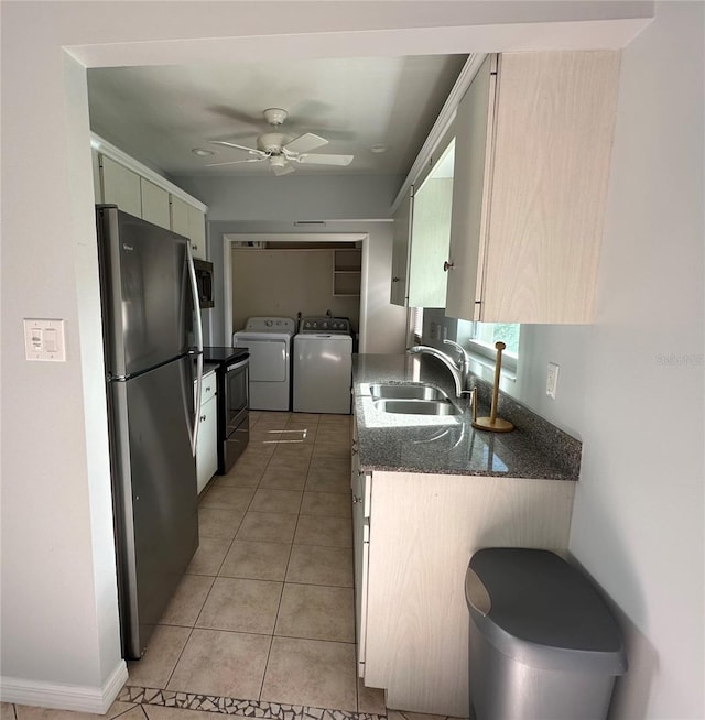 kitchen with light tile patterned flooring, stainless steel appliances, a sink, a ceiling fan, and washing machine and clothes dryer