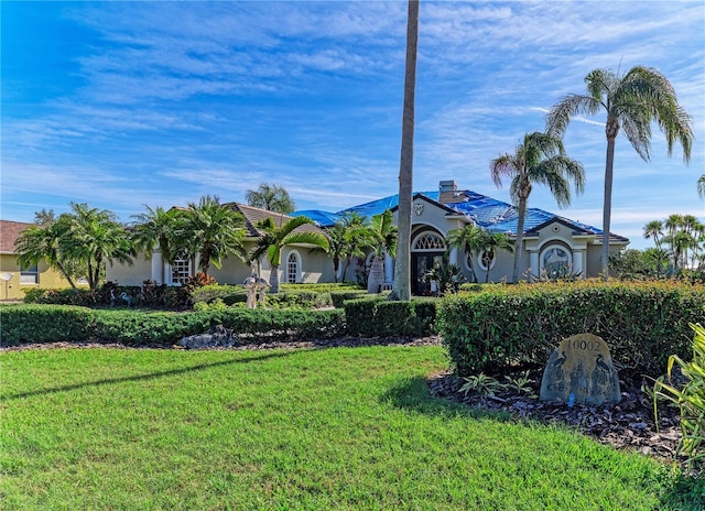 view of front of property with a front yard, a chimney, and stucco siding