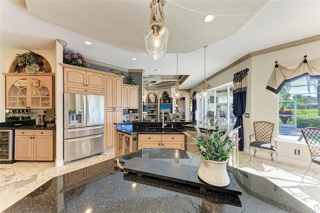 kitchen with stainless steel refrigerator with ice dispenser, a sink, glass insert cabinets, and pendant lighting