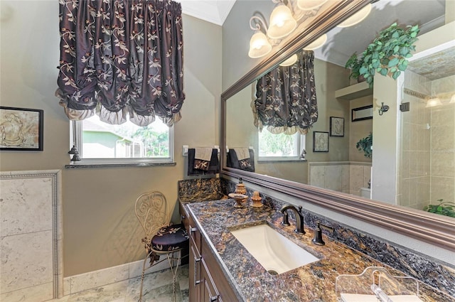 bathroom featuring a tile shower, crown molding, and vanity