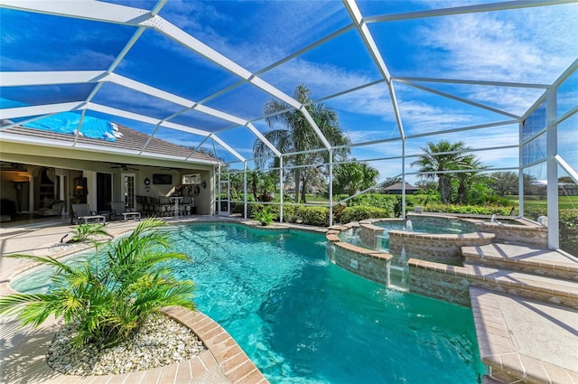 view of pool with ceiling fan, a patio, a lanai, and a pool with connected hot tub