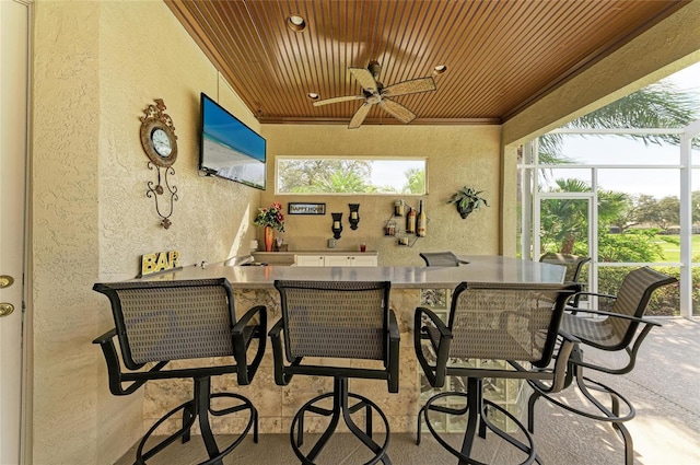 view of patio / terrace with glass enclosure, a ceiling fan, and outdoor wet bar