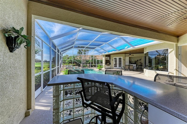 view of patio / terrace featuring a lanai, an outdoor pool, an outdoor bar, and french doors