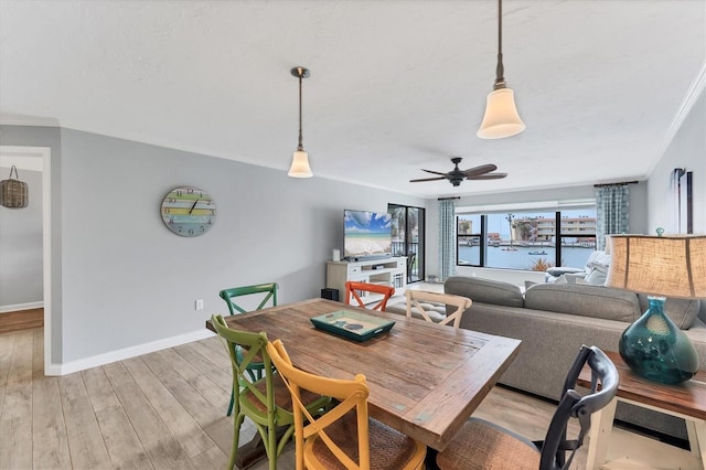 dining room with light wood-style floors, crown molding, baseboards, and a ceiling fan