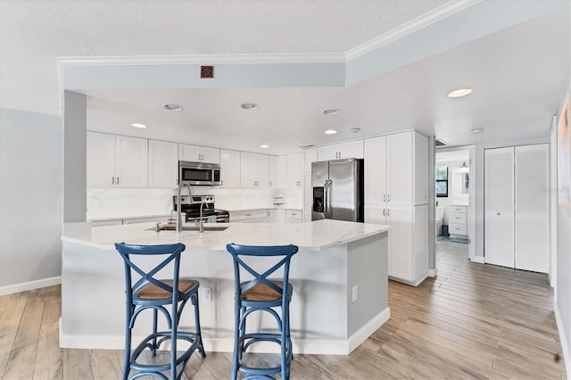 kitchen featuring stainless steel appliances, a sink, white cabinetry, and light wood-style floors