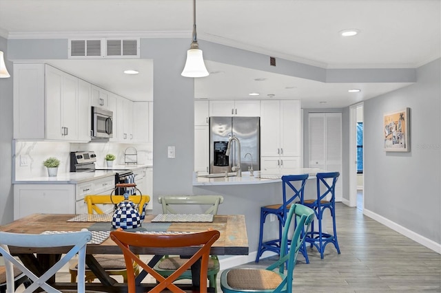 dining space featuring light wood-type flooring, visible vents, crown molding, and baseboards