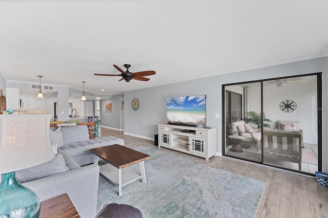 living room with visible vents, ceiling fan, baseboards, and wood finished floors