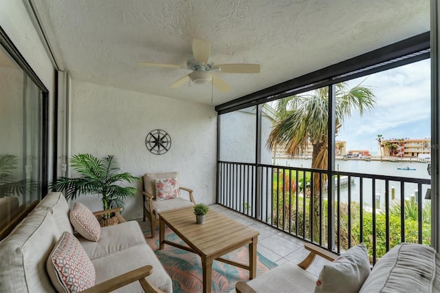 sunroom featuring ceiling fan and a water view