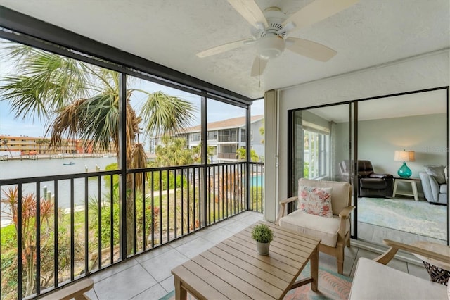 sunroom / solarium with ceiling fan and a water view