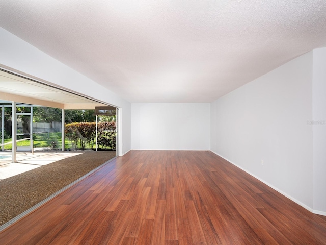 unfurnished living room featuring a textured ceiling, wood finished floors, and baseboards