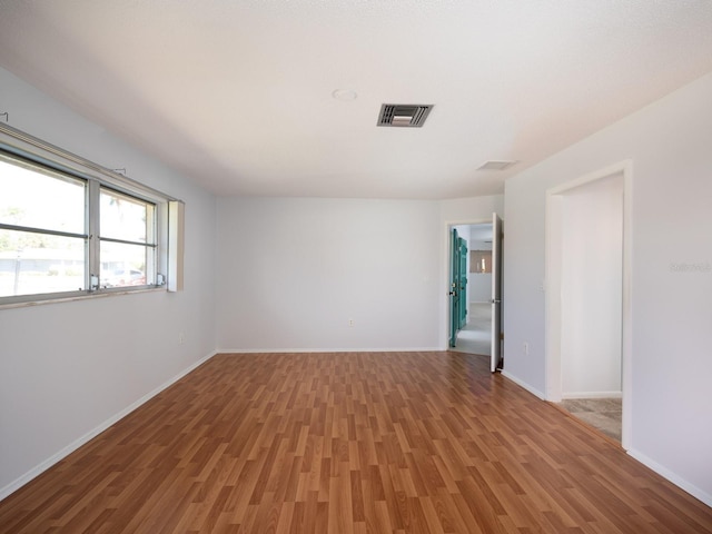 spare room featuring baseboards, visible vents, and wood finished floors