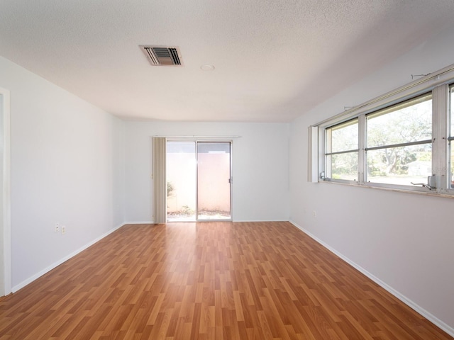 spare room featuring a healthy amount of sunlight, light wood finished floors, and visible vents