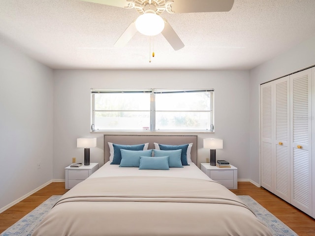 bedroom featuring a textured ceiling, a closet, light wood-style flooring, and baseboards