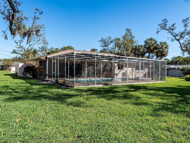 rear view of property with a yard, a lanai, and an outdoor pool