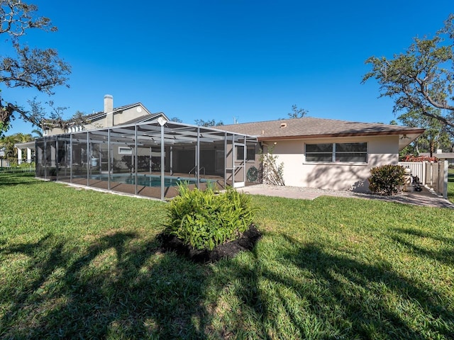 back of property with glass enclosure, a lawn, an outdoor pool, and stucco siding