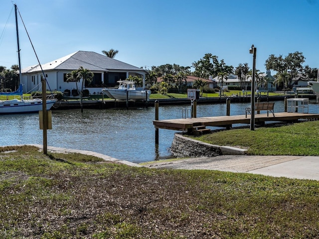 view of dock featuring a lawn, a water view, and a residential view
