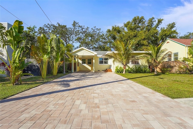 view of front of house with a front yard, decorative driveway, and fence