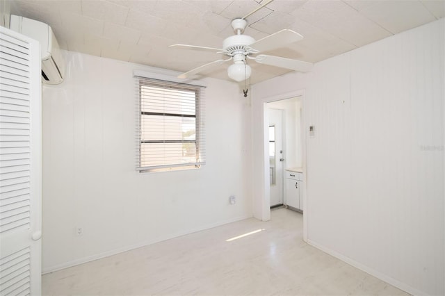 unfurnished bedroom featuring ceiling fan, baseboards, and a wall mounted air conditioner