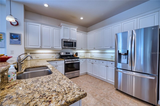 kitchen featuring stainless steel appliances, white cabinetry, a sink, and hanging light fixtures