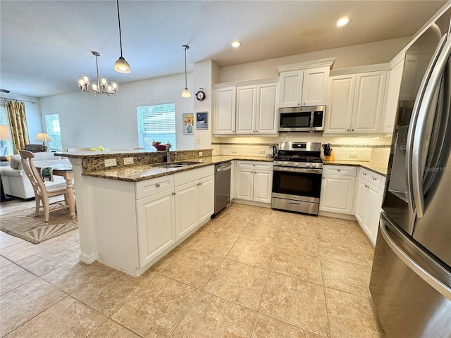 kitchen featuring white cabinets, appliances with stainless steel finishes, a peninsula, pendant lighting, and a sink