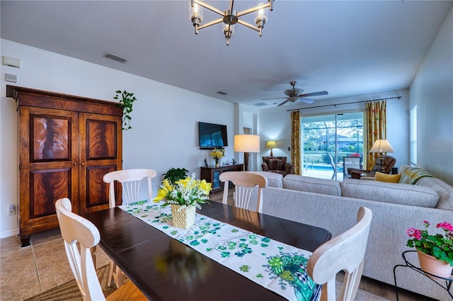 dining area featuring light tile patterned floors, visible vents, and ceiling fan with notable chandelier